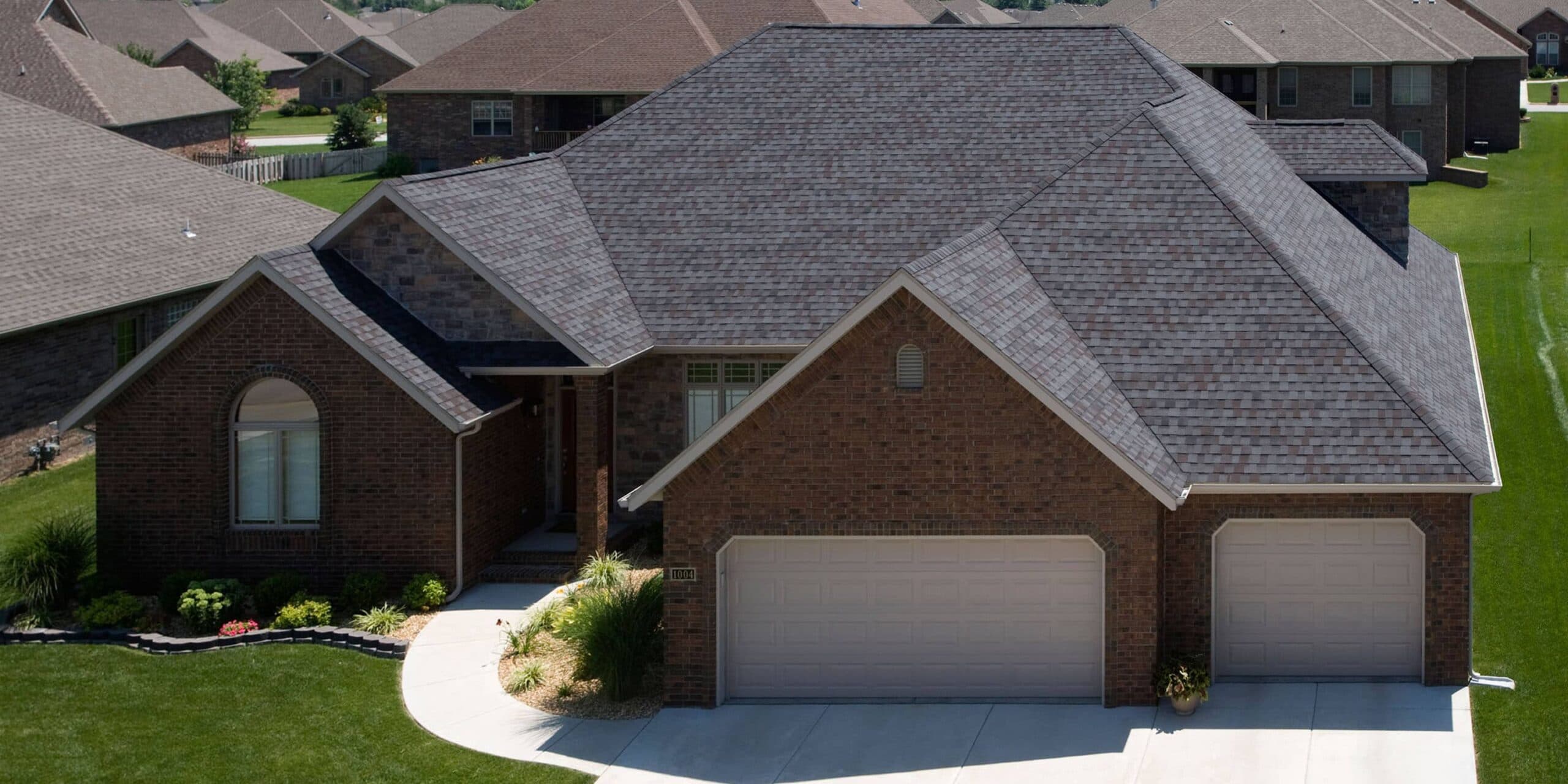 Roofing contractor inspecting a worn asphalt shingle on a home in Lee's Summit